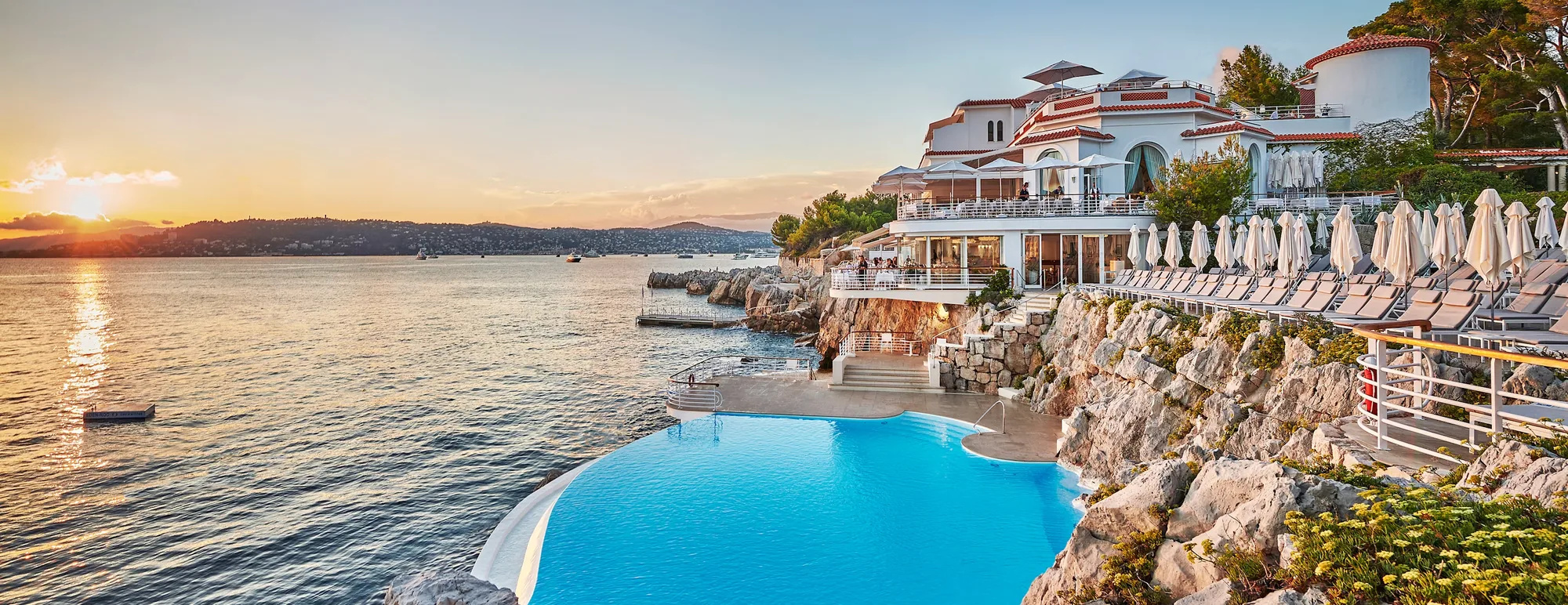 La piscine de l'Hotel du Cap-Eden-Roc taillee dans la roche au coucher du soleil