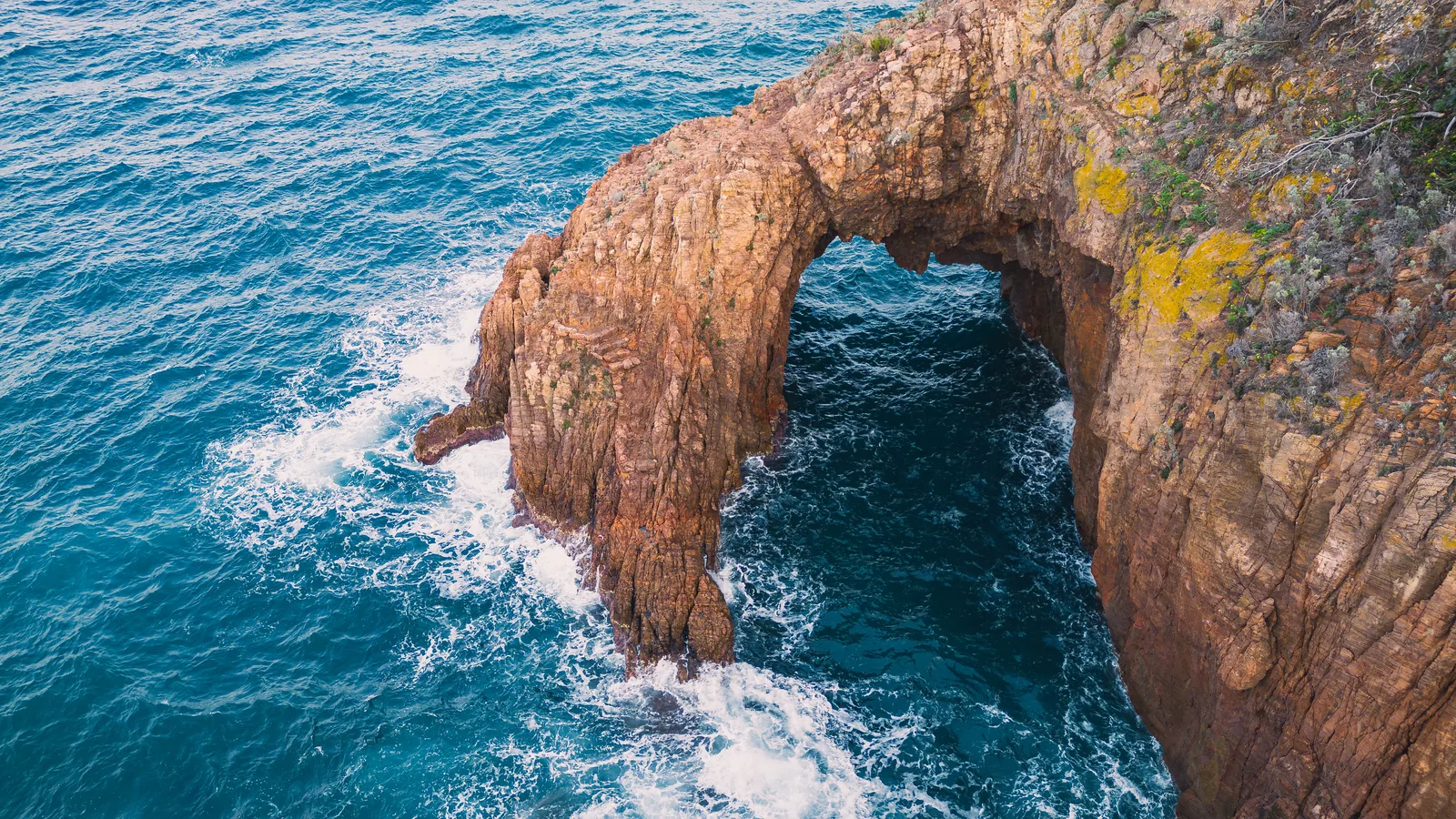 Arche naturelle de porphyre rouge creusee par la houle dans l'Esterel