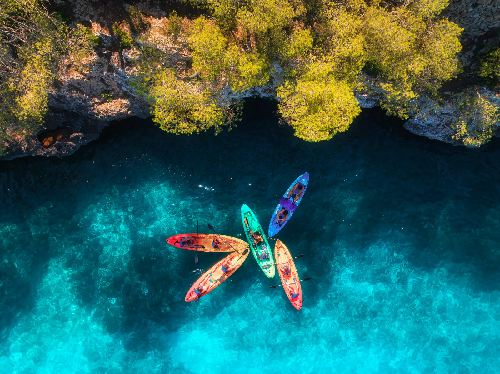 Kayaks colorés sur une eau turquoise le long de la côte