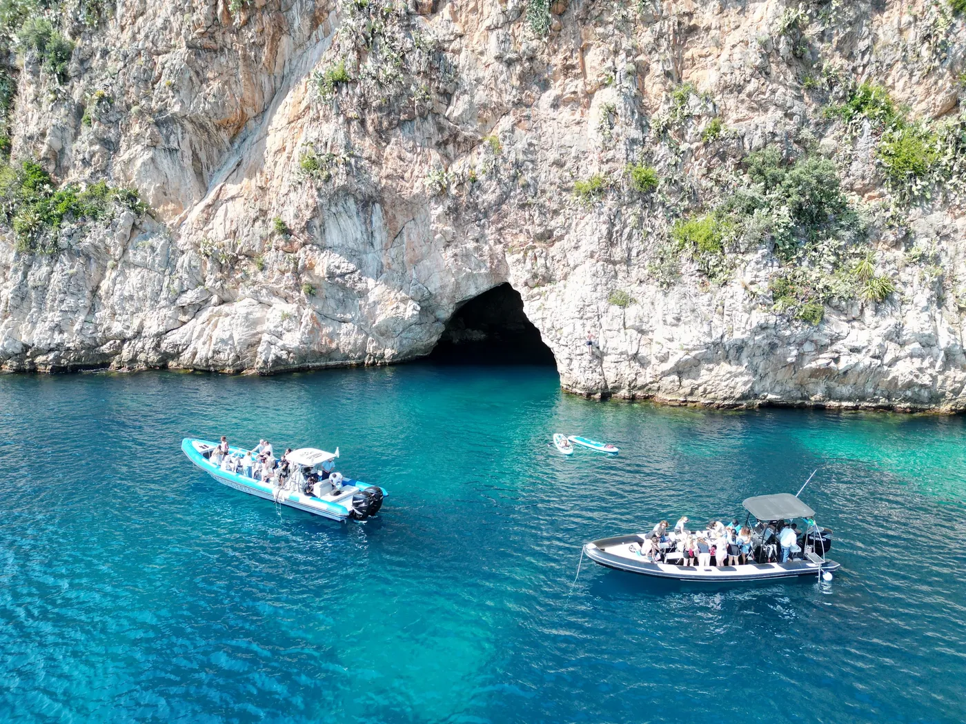 Des bateaux devant une grotte marine aux eaux turquoise pres de la Mala