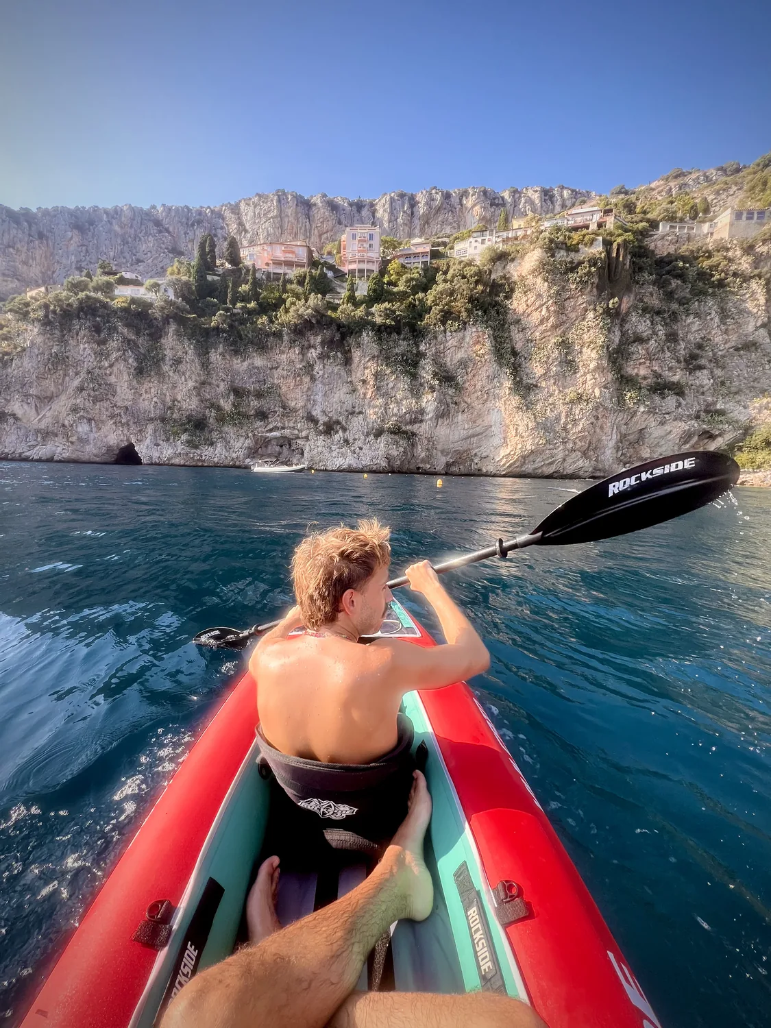 En kayak sur l'eau turquoise le long des falaises de la Mala