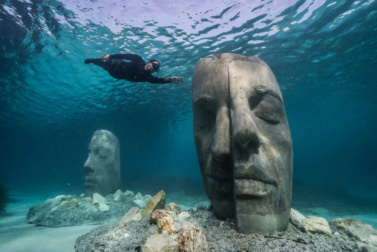 Un apneiste survole les visages immerges de l'ecomusee sous-marin de Sainte-Marguerite