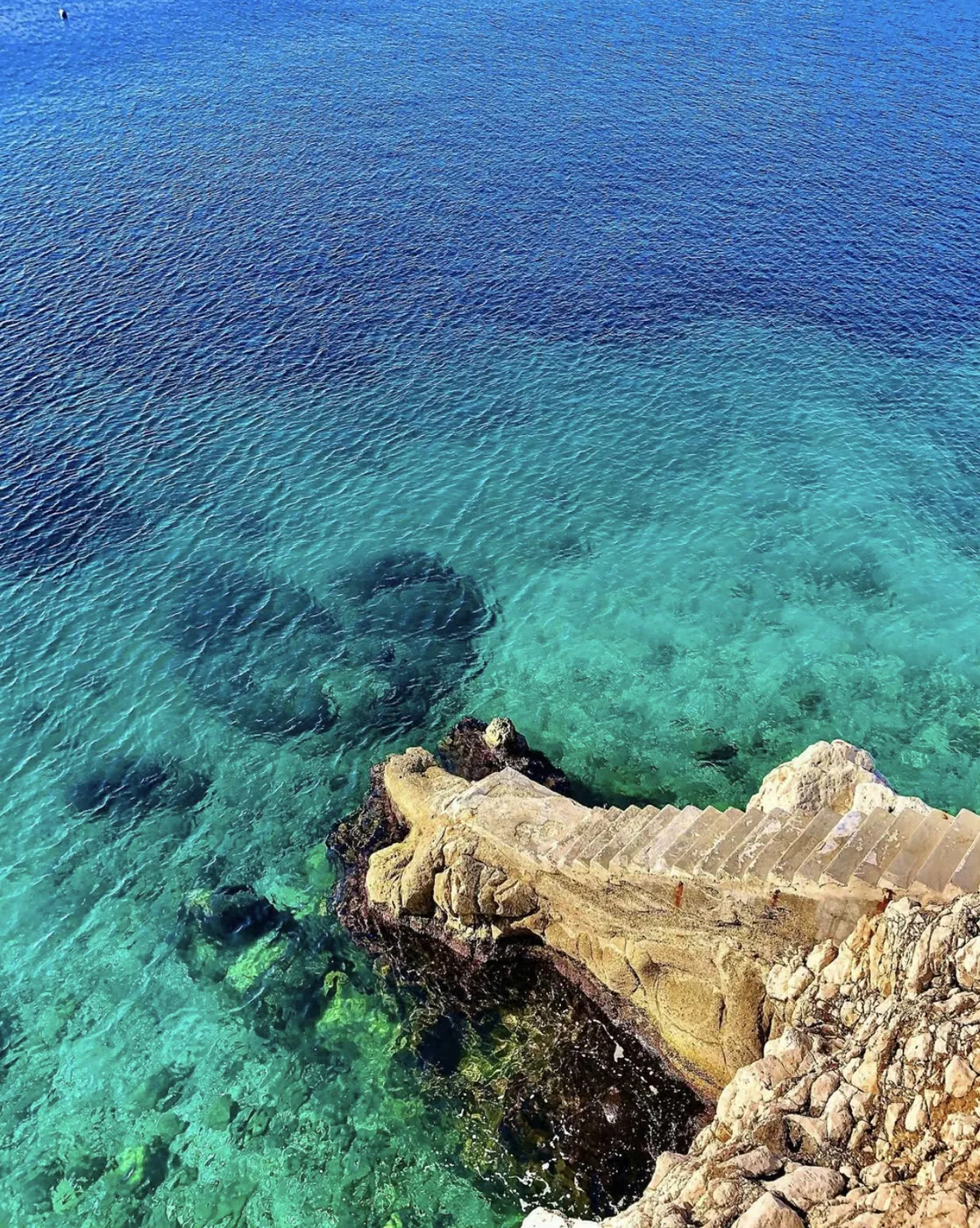 L'escalier de pierre qui plonge dans l'eau claire de Coco Beach au Cap de Nice