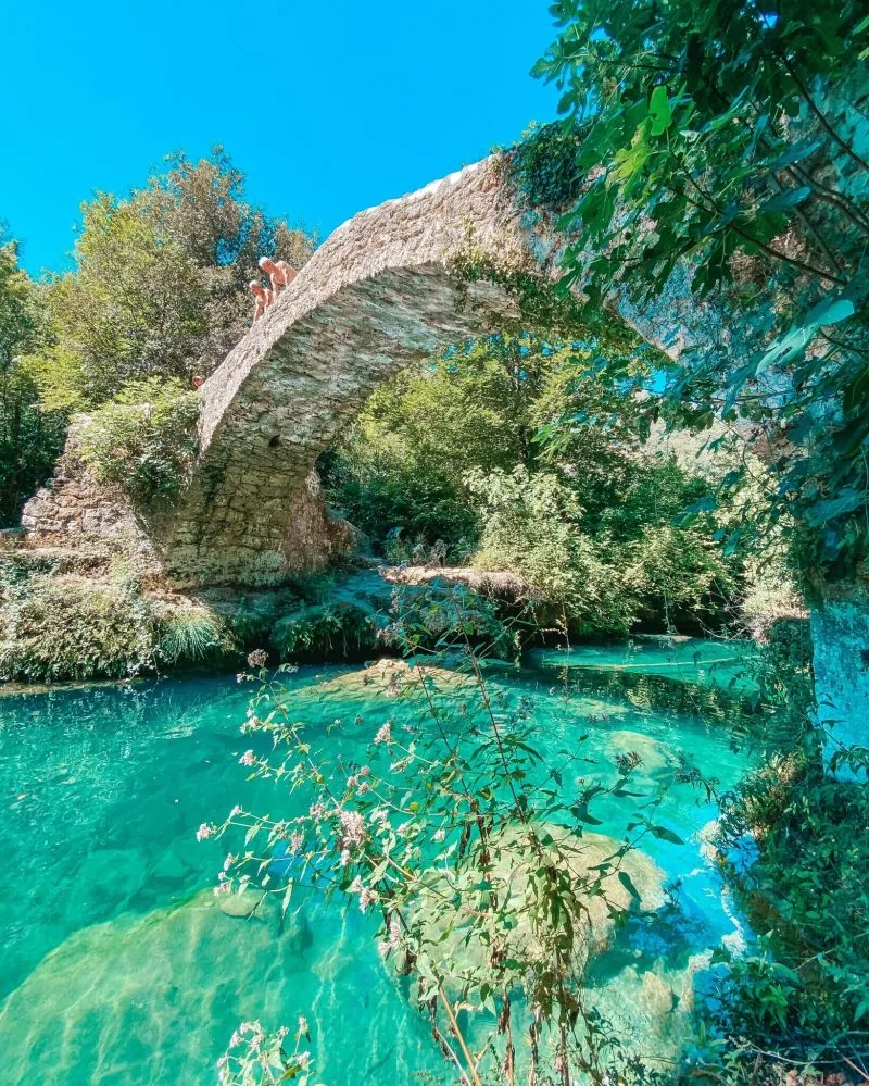 Le vieux pont de pierre des Tuves enjambant une eau turquoise, vu d'en bas